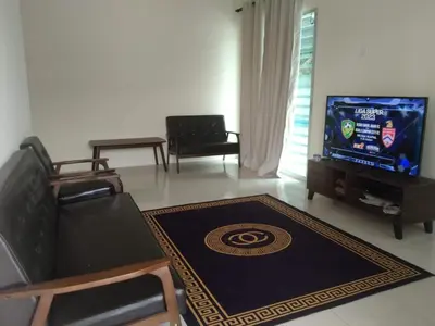 a living room with a couch and a tv at Homestay Mohamad & Delisha Tapah -Pool in Tapah