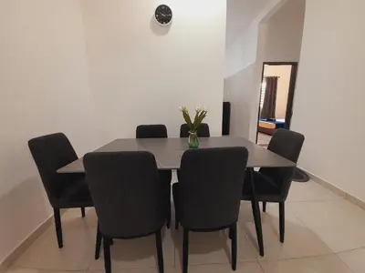 a dining room table with chairs and a vase of flowers on it at Afna Home stay in Kuala Lipis