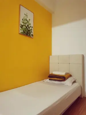 a bed in a room with a yellow wall at Sabai Sabai Guesthouse in Bayan Lepas in Bayan Lepas