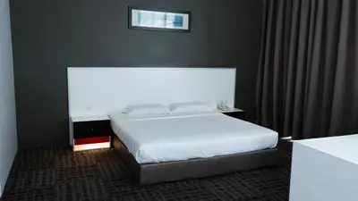 a bedroom with a white bed and a window at Beverly Hotel in Taiping