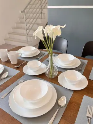 a wooden table with white plates and flowers in a vase at Aloft Cameron Highlands B in Brinchang