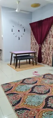 a table in a room with a rug and a clock at D'HutHomestay Puncak Iskandar in Seri Iskandar
