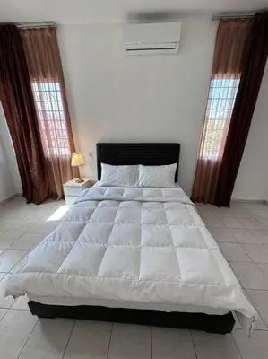 a white bed in a bedroom with two windows at Ipoh Luxury Spacious Corner Home in Ipoh