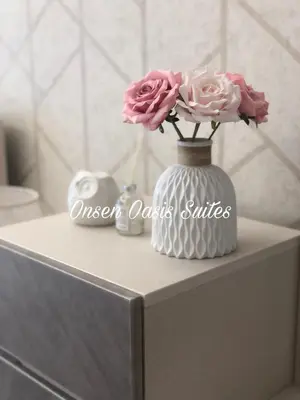a white vase with pink flowers on a counter at Onsen Oasis Premium Suites in Tambun