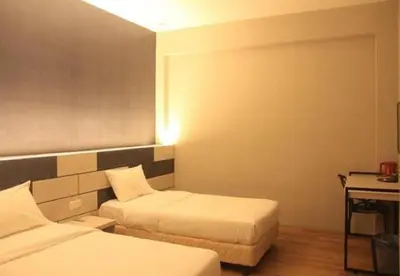 a hotel room with two beds and a desk at Merge Summit by Secoms in Teluk Intan