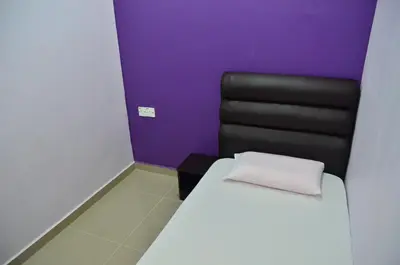 a bedroom with a bed and a black chair at Deena Hotel Bajet in Gua Musang