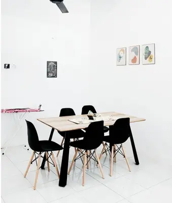 a dining room table with black chairs and a white wall at D' Splash Garden Homestay in Baling