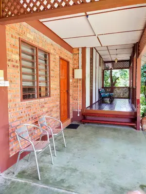 a patio with two chairs and a brick wall at D'Impiana Riverview Chalet # Lenggong in Kampong Ulu Jepai