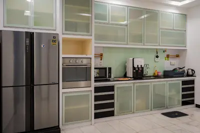a kitchen with white cabinets and a stainless steel refrigerator at GARDEN COZY2STOREY HOME 4ROOM 10PAX@NEAR ALMAJUSCO in Bukit Mertajam