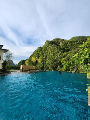 a pool of blue water with a mountain in the background at Sunway onsen suite ipoh in Ipoh