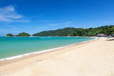 a beach with a group of people in the water at Affordable Cozy Apartment @ Coral Bay Resort in Pasir Bogak