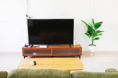 a living room with a flat screen tv on a table at monstera homestay (Lenggong) in Kampong Ulu Jepai