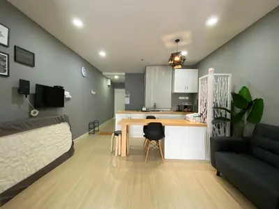 a living room with a table and a couch and a kitchen at A Modern & Homely Studio with Pool and Gym in Kampar