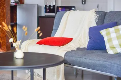 a blue couch with red and white pillows and a table at The Octagon Ipoh -- In the Heart of the City in Ipoh