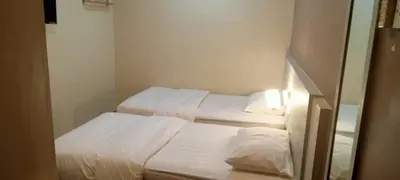two beds in a small room with white sheets at Spring Inn Hotel in Sungai Petani