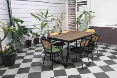a table and chairs on a checkered floor with plants at British Granny's Cottage in Georgetown in Jelutong