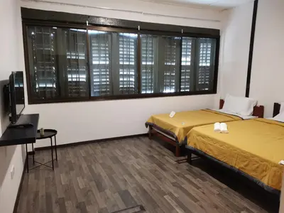 a room with two beds and a tv and a window at G FORTUNE GUEST HOUSE+ in George Town
