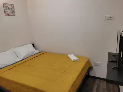 a bed in a room with a yellow blanket on it at G FORTUNE GUEST HOUSE+ in George Town