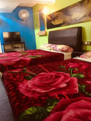a room with three beds with red sheets and roses at Lily Haven Hotel C-1 in Tanah Rata