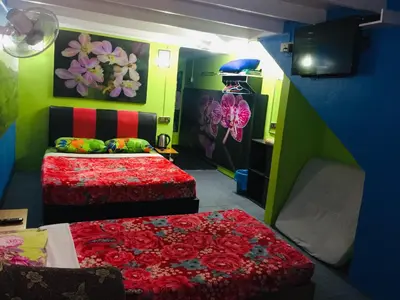two beds in a room with green and red at Lily Haven Hotel C-1 in Tanah Rata