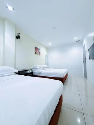 two beds in a room with white walls at Asia Green Hotel in Sungai Besar