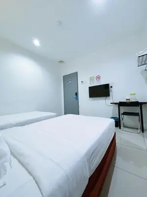 a white room with a bed and a television at Asia Green Hotel in Sungai Besar