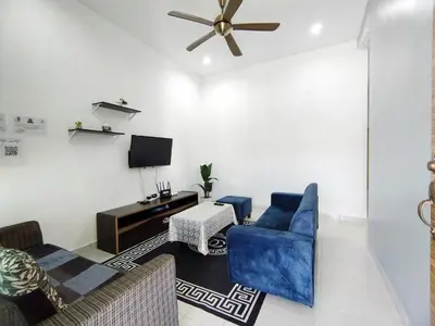 a living room with a blue couch and a tv at Indah Damai Homestay in Kepala Batas