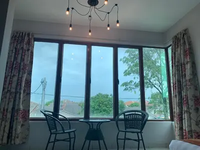 a dining room with a table and chairs in front of a window at White House Homestay in Ipoh