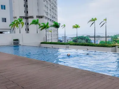 a person swimming in a swimming pool in a building at Strait Garden Family Suites by Maj in Jelutong