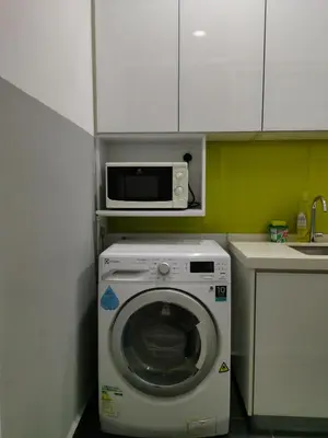 a kitchen with a washing machine and a microwave at Strait Garden Family Suites by Maj in Jelutong