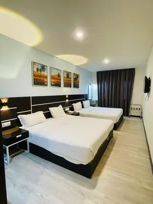 a hotel room with two beds and a desk at K Garden Hotel Parit Buntar in Parit Buntar