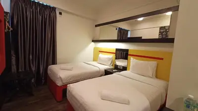 a hotel room with two beds and a mirror at Sense Hotel Taiping in Taiping