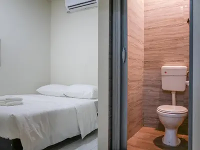 a bathroom with a toilet next to a bed at Aayu Chulia - Chulia St, George Town in George Town