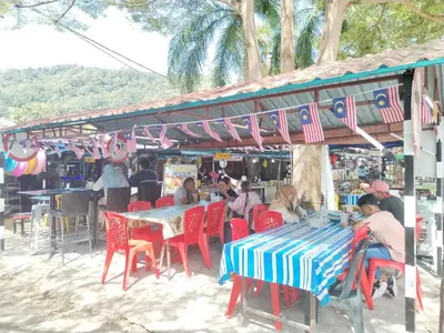 a group of people sitting at a table on the beach at Teluk Batik Holiday Apartment in Lumut