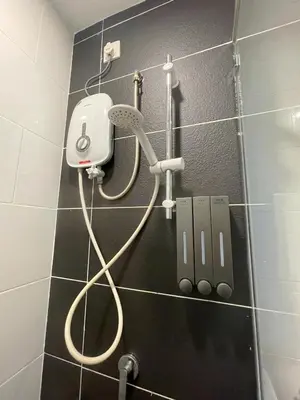 a shower in a bathroom with a hair dryer on a wall at JS Ipoh Homestay @ The Majestic Ipoh in Ipoh