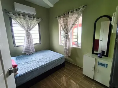 a small bedroom with a bed and two windows at Laman D'Arni in Sungai Besar