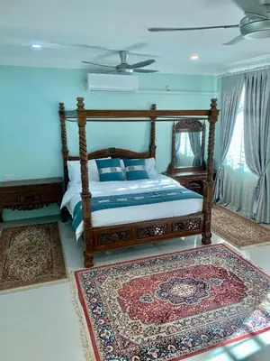 a bedroom with a wooden bed and a rug at Puncak Villa 10-20pax in Kuala Kangsar