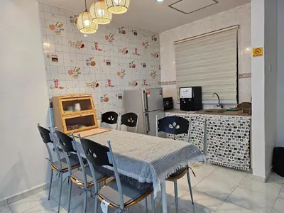 a kitchen with a table and chairs and a refrigerator at Fukuda Minshuku Japanese style in Lumut