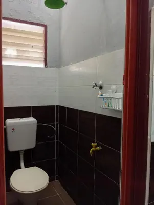 a bathroom with a white toilet and a window at Ekaira homestay in Tambun