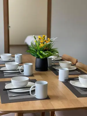 a wooden table with white dishes and a vase of flowers at Utopia Homestay @ Cameron Centrum in Cameron Highlands