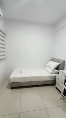 a white bedroom with a bed and a chair at Honeyz Waterpark Homestay. in Ipoh