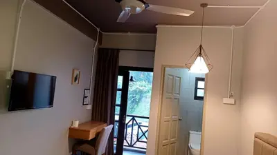a living room with a ceiling fan and a television at BRICKS Cameron Hostel in Tanah Rata