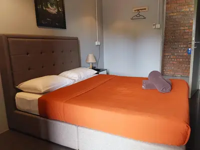 a bedroom with a large bed with an orange blanket at BRICKS Cameron Hostel in Tanah Rata