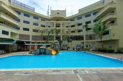 a pool in front of a large building with a slide in front at Coral Bay \u5c0f\u578b\u516c\u5bd3 in Pasir Bogak