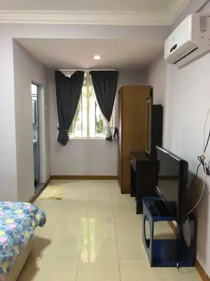 a room with a bed and a desk and a window at Supreme Homestay in George Town