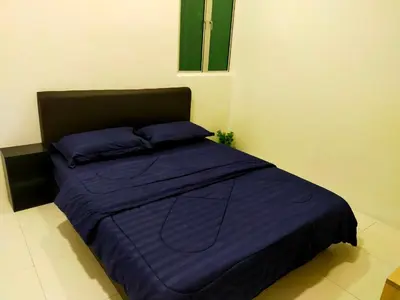 a bed with purple sheets and pillows in a room at Homestay Manitha in Seri Manjung
