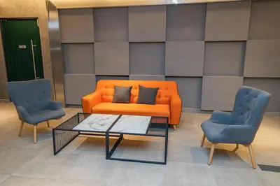 an orange couch and two chairs and a coffee table at Ipoh Tambun Lost World Sunway Onsen Mina 3R2B 8pax in Tambun