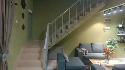 a living room with a staircase with a couch and chairs at HOMESTAY Rezeki in Batu Gajah