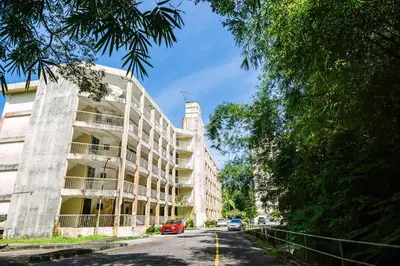 an apartment building on a street with cars parked at EE's Sunset House - Homestay 3 min walk to beach in Batu Ferringhi