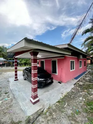 a car parked in front of a red house at Rumah Comel in Kampung Degong